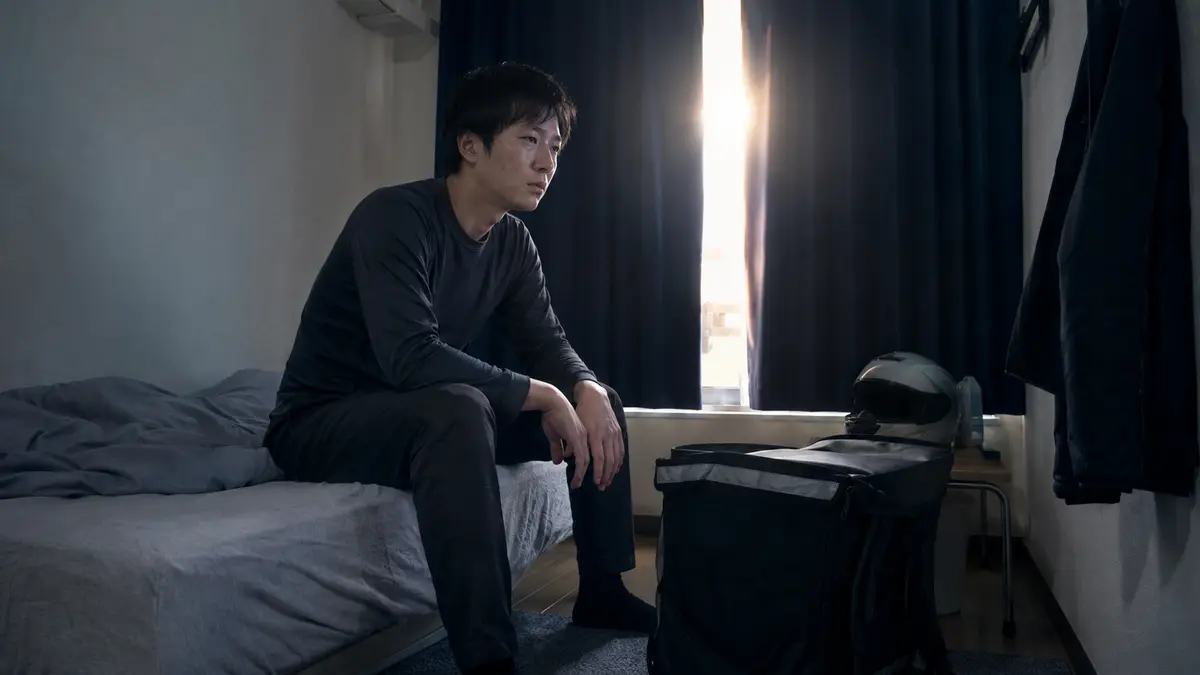 夜勤と配達を終えた後、昼に近づく日差しの中で眠れず、寮のベッドに座る30代男性